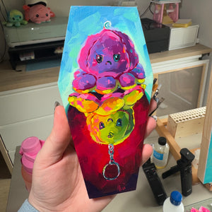 Original oil painting by Alai Ganuza titled "Buried Emotions". A reversible octopus plushie painted on a coffin-shaped wood canvas. Gothic cute art.