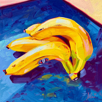 Original oil painting by Alai Ganuza titled "Banana Bunch". A cluster of three ripe yellow bananas with a produce sticker resting on a deep blue surface, painted on a square wood panel.