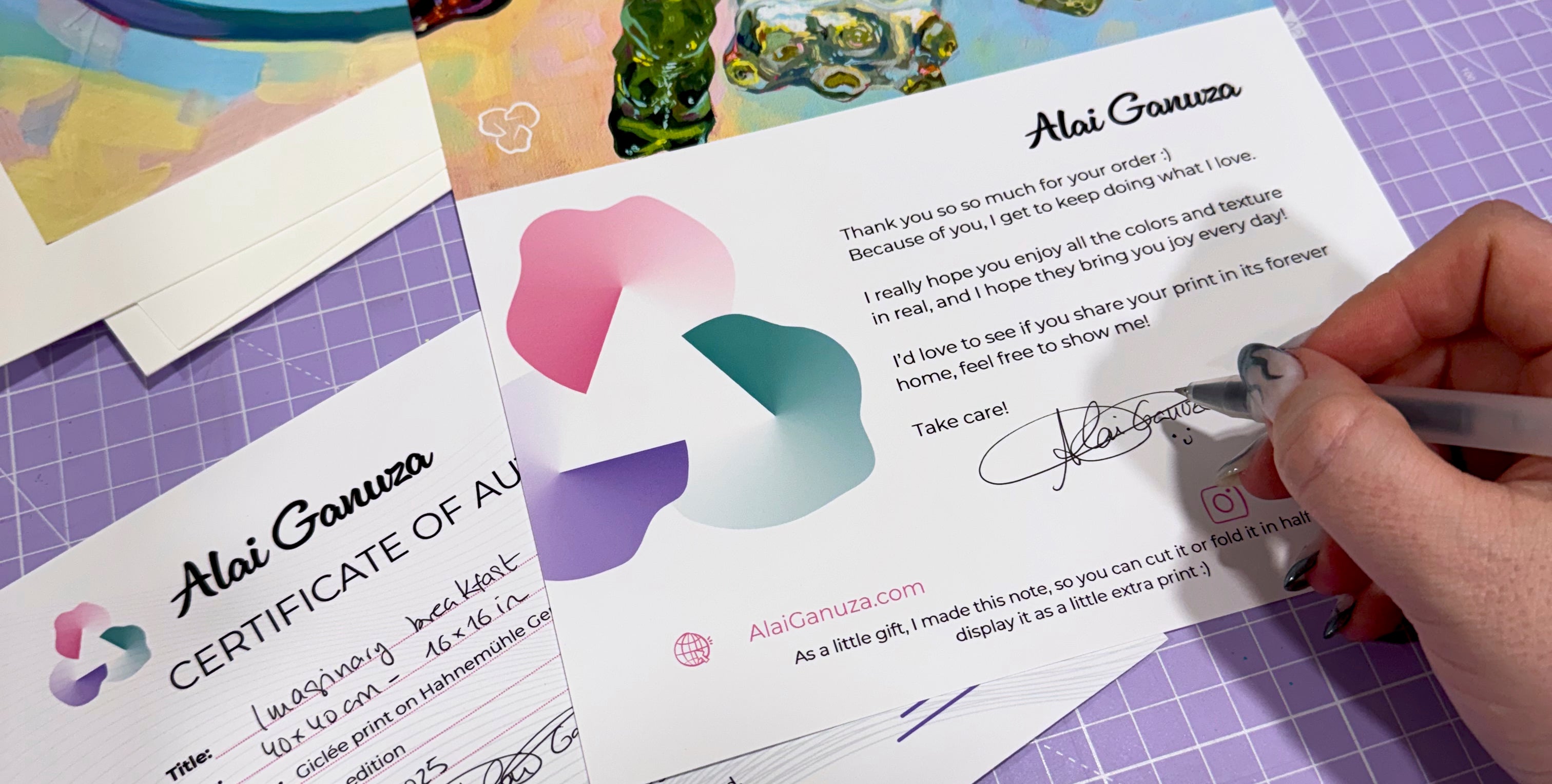 Artist Alai Ganuza signing a Certificate of Authenticity and personalized thank-you letter for fine art prints, featuring her logo, signature, and handwritten details.