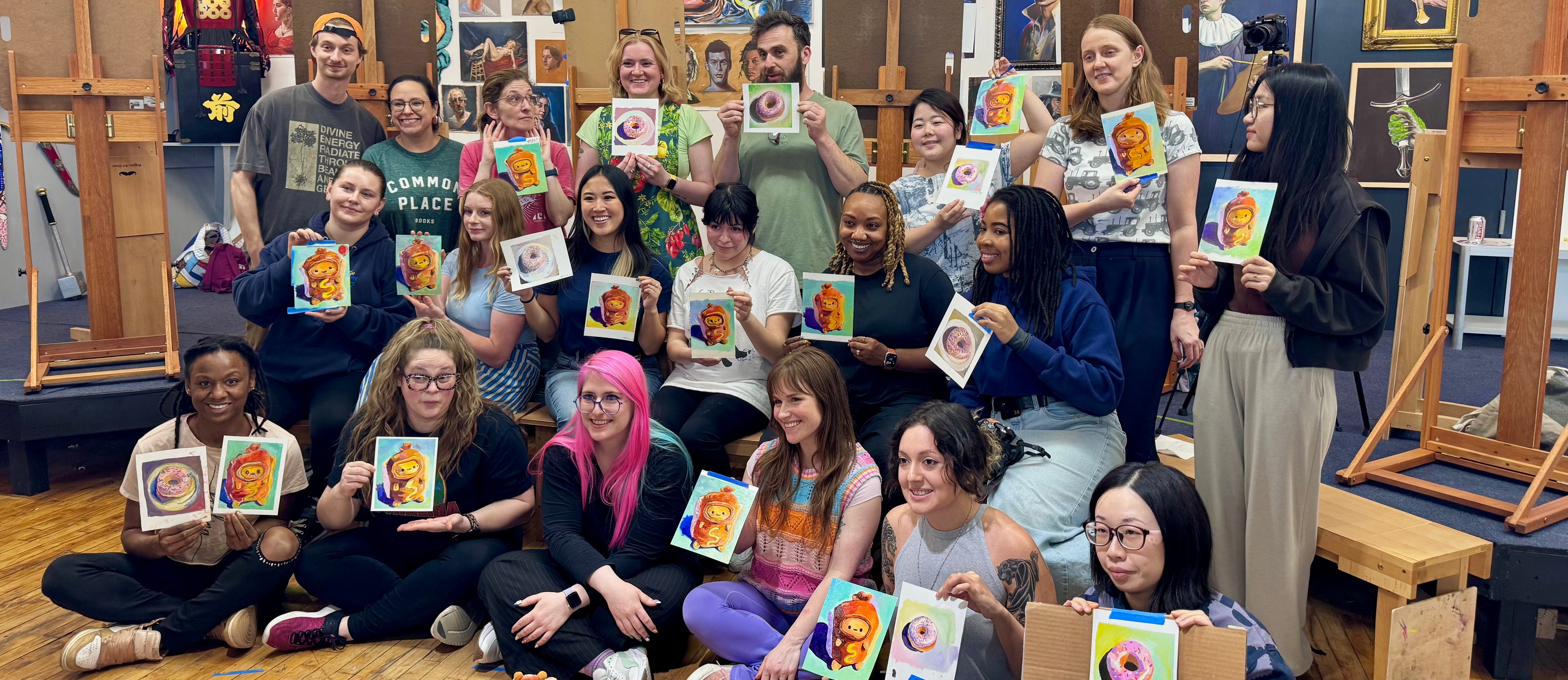 Group photo from Alai Ganuza’s painting workshop, showing participants smiling and holding their colorful finished artworks inside the studio.