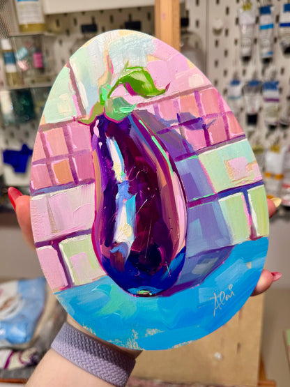 Alai holding the painting egg-plant. An eggplant painted on an egg-shaped canvas.