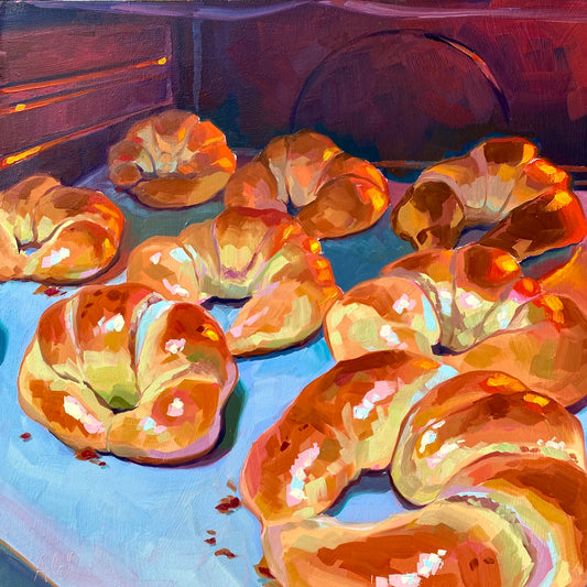 Original oil painting by Alai Ganuza titled "In the oven". A tray of golden-brown croissants baking inside an oven, illuminated by a warm orange glow with cool blue shadows on the baking sheet.