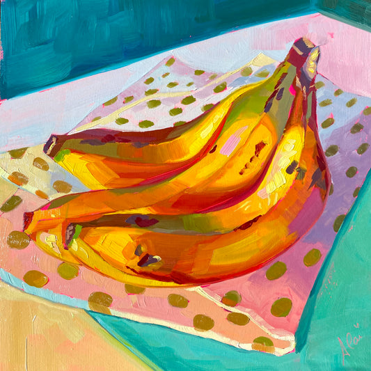 Original oil painting by Alai Ganuza titled "Bananas on pink". A bunch of three bananas on a pink polka-dot cloth, rendered in thick impasto with vibrant orange and yellow tones against a teal background.