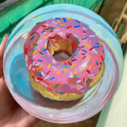 Original circular oil painting by Alai Ganuza titled "Sprinkle donut". A classic donut with thick pink frosting and colorful multi-colored sprinkles, rendered in heavy impasto on a light blue and lavender background.