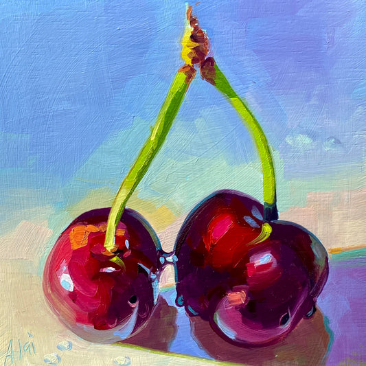 Original oil painting by Alai Ganuza titled "Kissing cherries". Two ripe, deep red cherries touching at the base, connected by bright green stems, set against a light lilac and blue background.