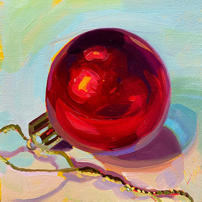 Original oil painting by Alai Ganuza titled "Red Christmas Ball (Matte)". A smooth, satin-finish red Christmas ornament with soft pink highlights and a gold ribbon, painted on a square wood panel against a pastel blue background.