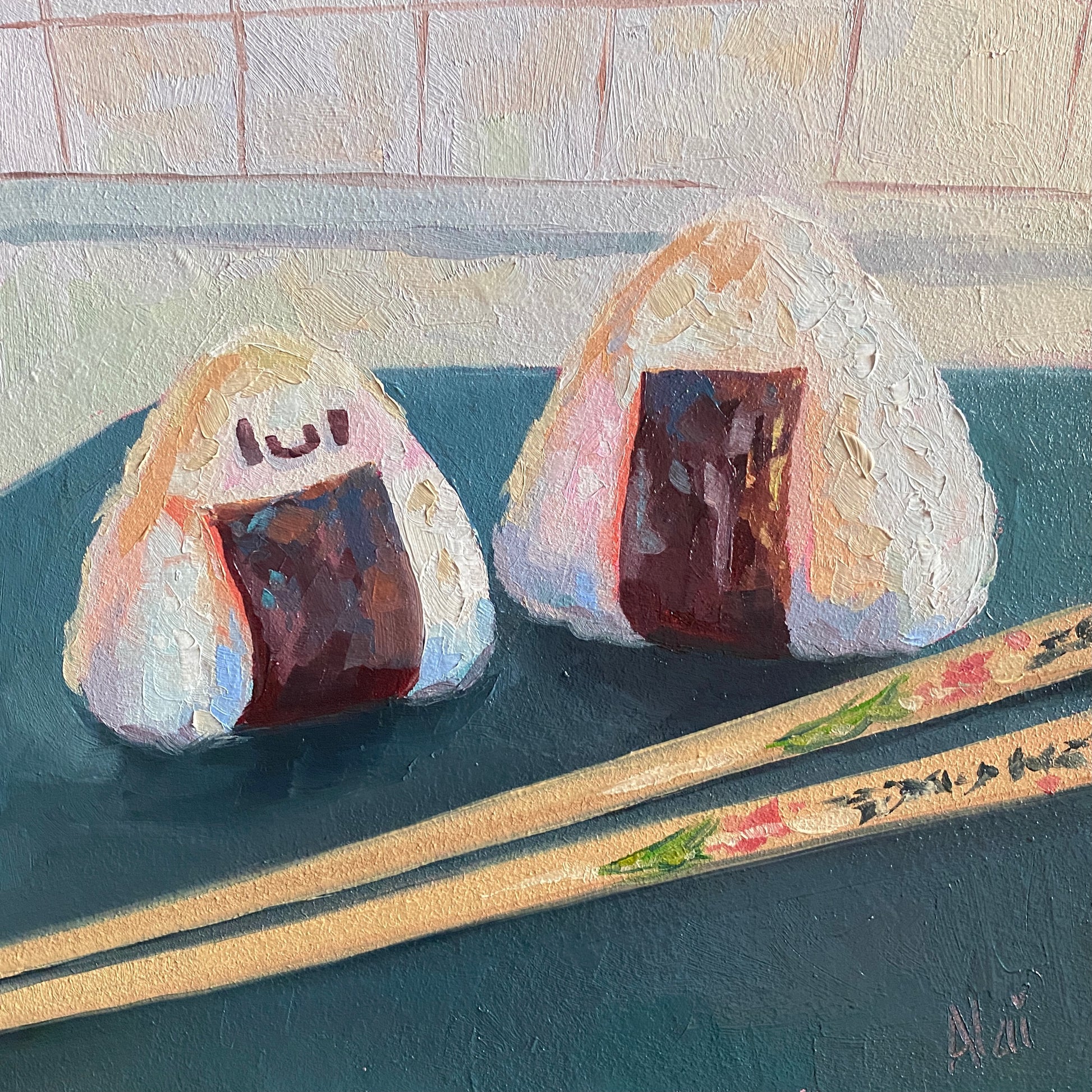 Original oil painting by Alai Ganuza titled "Onigiri/Rice balls". Two triangular rice balls with dark seaweed wraps—one with a cute smiley face—resting on a dark teal surface with decorated wooden chopsticks.
